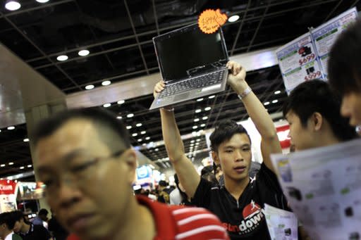 A sales clerk holds up a laptop computer for sale during the annual PC Show on Friday, June 10, 2011 in Singapore. (AP Photo/Wong Maye-E)