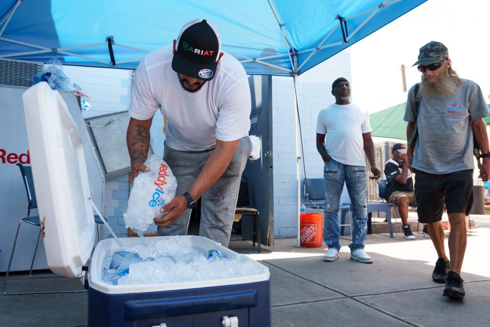 Justa Center volunteer Joel Diaz (left) fills a cooler with ice and water bottles as the center welcomes people in need of cooling down during a record-breaking heat wave on July 16, 2023, in Phoenix.