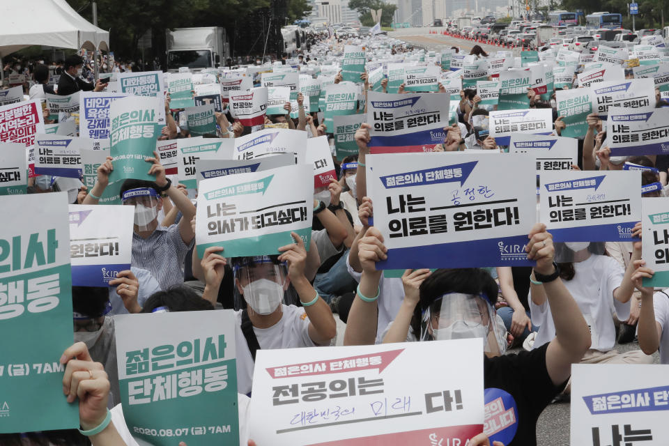 Interns and resident doctors hold up cards during a rally against the government medical policy in Seoul, South Korea, Friday, Aug. 7, 2020. Thousands of young doctors in South Korea began a strike Friday in protest of government medical policy, causing concerns about treatment of patients amid the coronavirus pandemic. The signs read: "Mass action by young doctors and I want to be a doctor." (AP Photo/Ahn Young-joon)