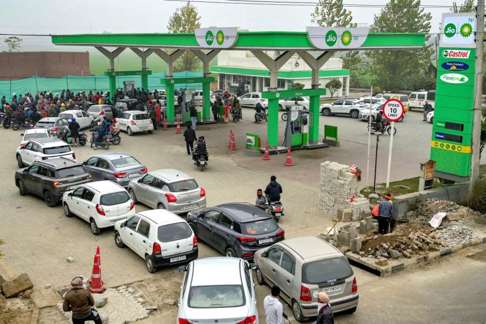 People with their vehicles wait in queues to refill fuel tanks at a fuel station in Amritsar on 2 January (AFP via Getty Images)