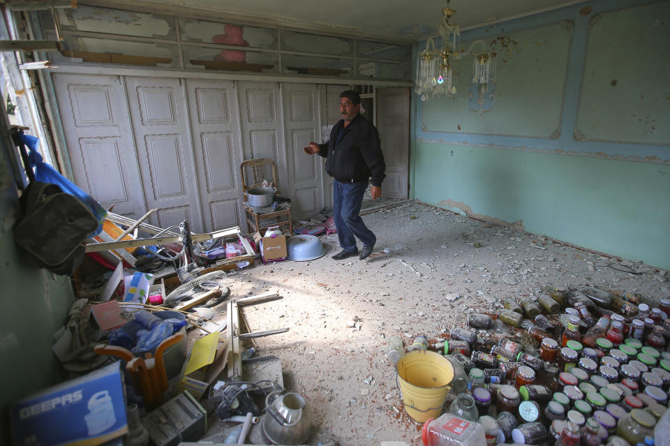 A local resident walks in an apartment building that was allegedly damaged by recent shelling during fighting over the breakaway region of Nagorno-Karabakh in Tartar region, Azerbaijan, Wednesday, Sept. 30, 2020. Leaders of Azerbaijan and Armenia brushed off the suggestion of peace talks Tuesday, accusing each other of obstructing negotiations over the separatist territory of Nagorno-Karabakh, with dozens killed and injured in three days of heavy fighting. (AP Photo/Aziz Karimov)