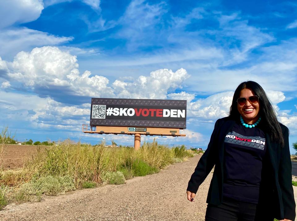 Angela Willeford, intergovernmental relations project manager for the Salt River Pima-Maricopa Indian Community, stands in front of a billboard with the phrase #SkoVoteDen, slang for "Let's go vote, then."