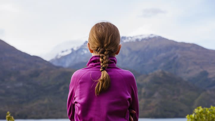 a red haired girl with a french braid looking at mountains