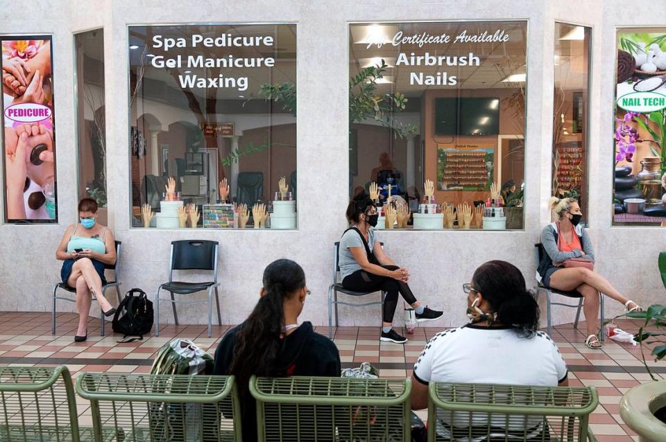 Customers sit with physical distancing and wear face masks as they wait for a manicure at Nail Tech in the Yuba Sutter Mall on Wednesday, May 6, 2020 in Yuba City. It was the first day the mall was open after the county health officials allowed retail stores to reopen in defiance of the state’s stay-at-home order to slow the spread of the coronavirus.