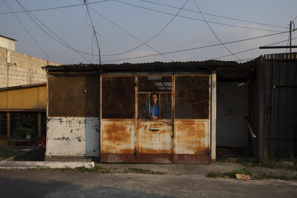 Un hombre mira al exterior desde su casa tras la imposición de una orden que prohíbe salir a la calle para ayudar a evitar la propagación del nuevo coronavirus, en el vecindario de La Chacra, en la Ciudad de Guatemala, el 27 de marzo de 2020. (AP Foto/Moisés Castillo)