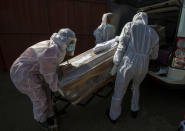 FILE - In this July 21 2020 file photo, funeral home workers in protective suits carry the coffin of a woman who died from COVID-19 into a hearse in Katlehong, near Johannesburg, South Africa. The country's success in bringing its first wave of COVID-19 under control has allowed it to almost fully reopen the economy, while monitoring for signs of a second surge, says the government's chief medical advisor. (AP Photo/Themba Hadebe, File)