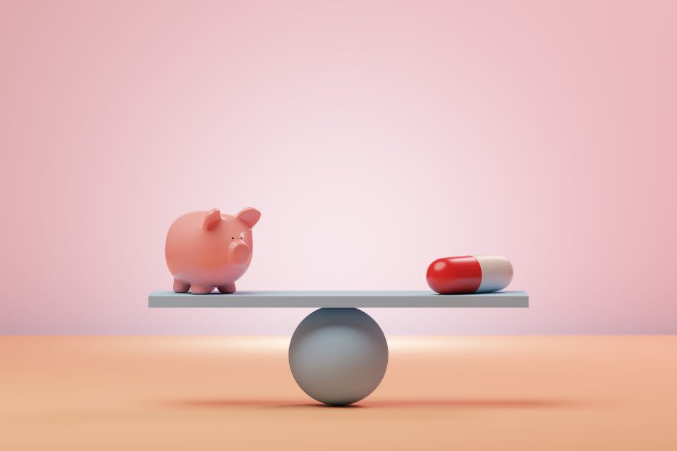 Conceptual image of a seesaw with a piggybank and an oversized pharmaceutical pill balancing on it