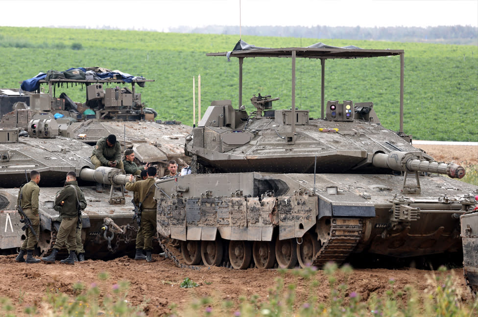 Israeli army troops stand around their tanks in an area along the border with the Gaza Strip in southern Israel on 10 April 2024