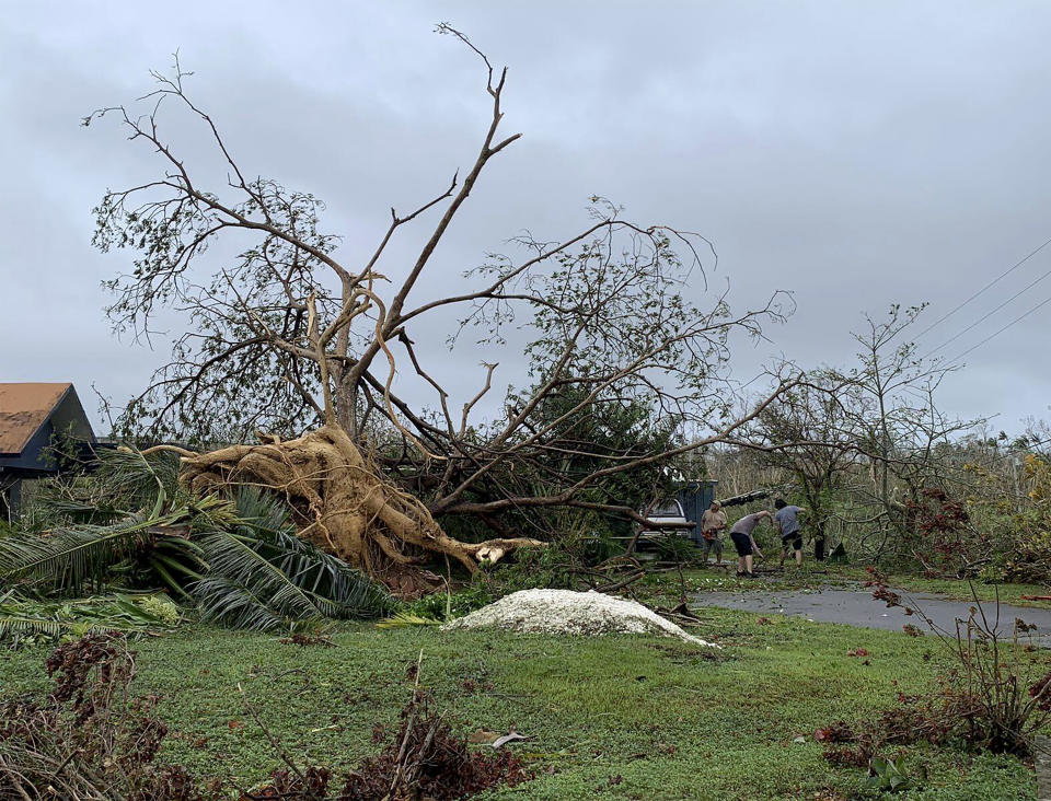 Andy Villagomez despeja los restos de un enorme árbol que se encontraba frente a su casa antes de ser derribado por los vientos del tifón Mawar, el jueves 25 de mayo de 2023, en Mongmong-Toto-Maite, Guam. (AP Foto/Grace Garces Bordallo)