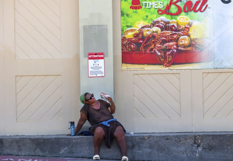 A woman fans herself underneath a crawfish sign outside a grocery store in New Orleans. (Chris Granger/The Advocate via AP)