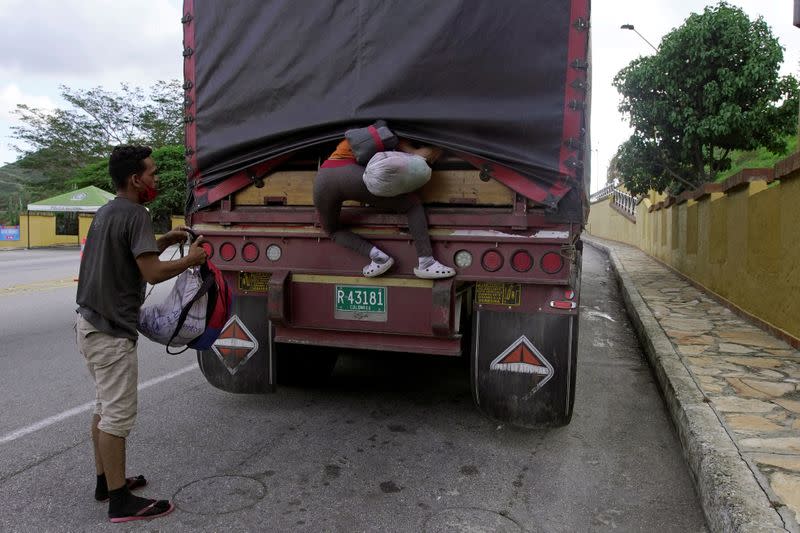 Venezuelan migrants climb a truck in Aracota