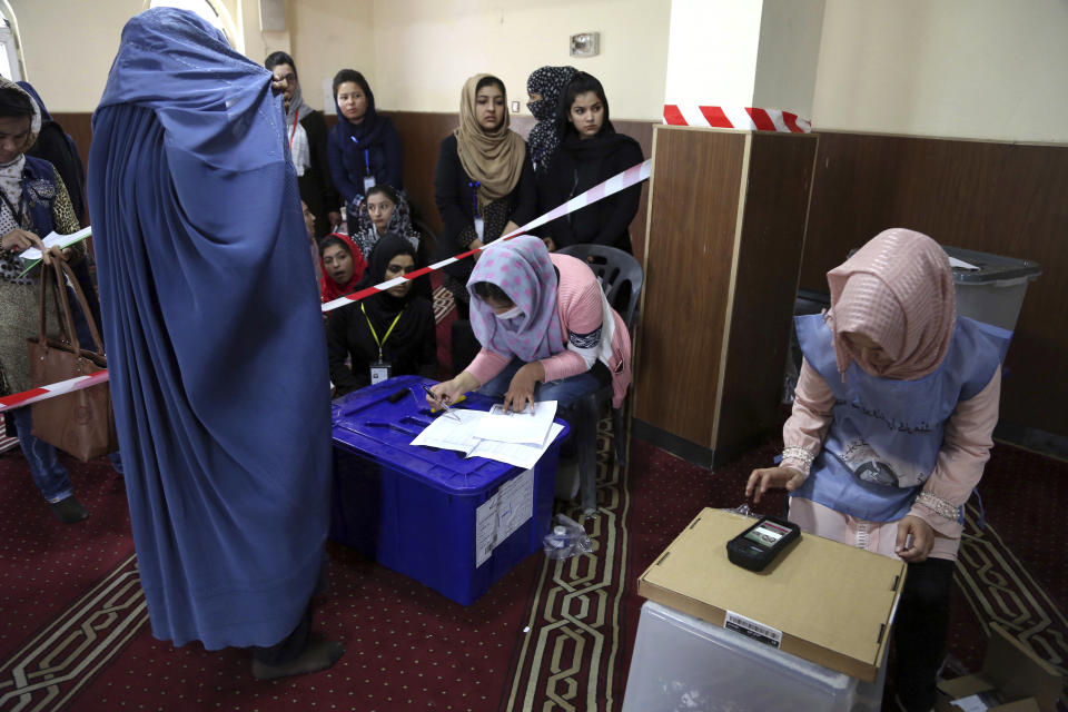 An Afghan woman left, registers to cast their votes during the Parliamentary elections in Kabul, Afghanistan, Saturday, Oct. 20, 2018. Tens of thousands of Afghan forces fanned out across the country as voting began Saturday in the elections that followed a campaign marred by relentless violence. (AP Photo/Rahmat Gul)