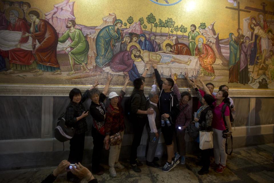 Christian pilgrims pose for a photo prior to the Easter Sunday mass at the Church of the Holy Sepulchre, traditionally believed by many to be the site of the crucifixion and burial of Jesus Christ, in Jerusalem's Old City, Sunday, April 20, 2014. Millions of Christians around the world are celebrating Easter, commemorating the day when according to Christian tradition Jesus was resurrected in Jerusalem two millennia ago. (AP Photo/Sebastian Scheiner)