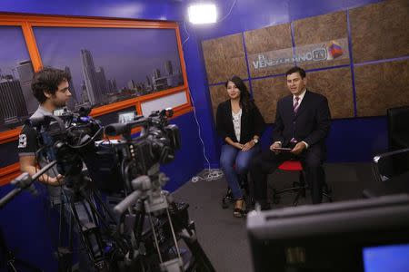 Fredy Machado, 42, a Venezuelan who has been living in the U.S. for five years and Susana Peres, 30, with three weeks, present the news at the El Venezolano internet broadcast TV channel in Miami April 29, 2014. REUTERS/Carlos Garcia Rawlins