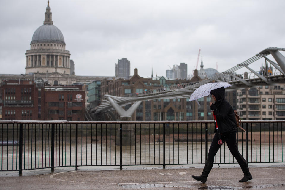 A woman shelters under an umbrella on the South Bank within view of St Paul's Cathedral. (Getty)