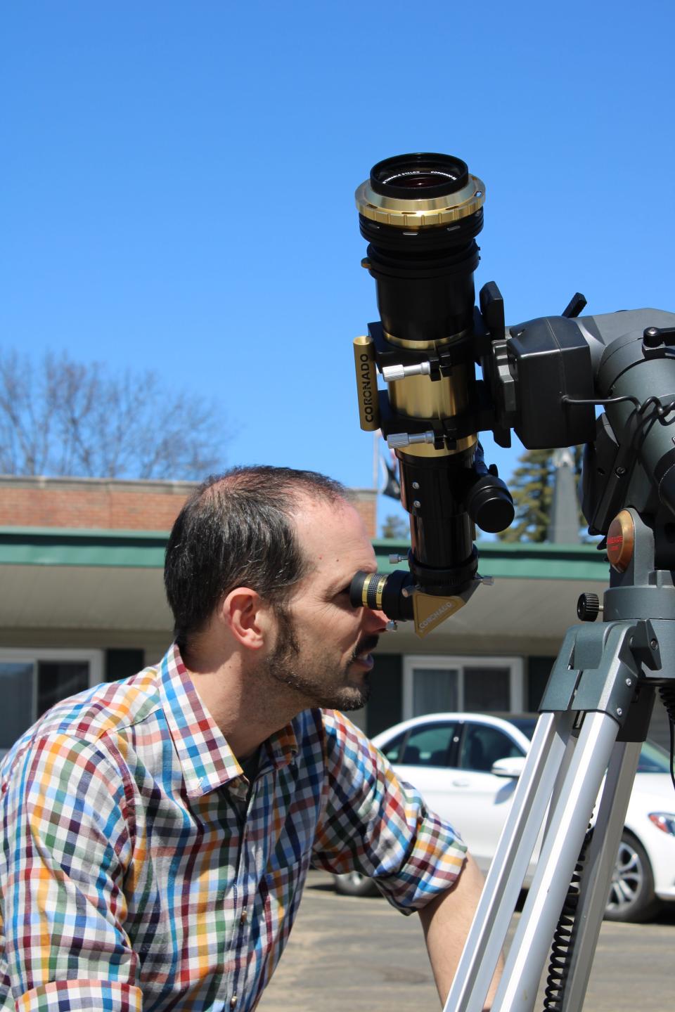 Professor Brad Moser peers through his telescope, set up to watch the eclipse.