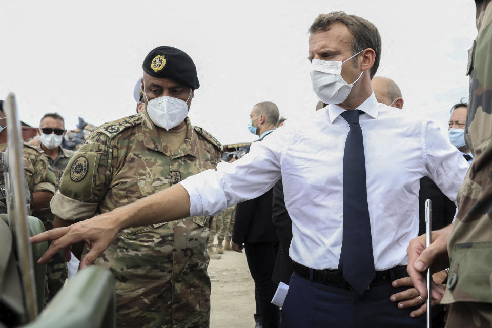 French President Emmanuel Macron gestures toward a board as he meets the military mobilized to help to rebuild the port of Beirut, Tuesday, Sept.1, 2020. President Emmanuel Macron issued a stern warning to Lebanon's political class, urging them to commit to serious reforms within few months or risk punitive action including sanctions, if they fail to deliver. (Stephane Lemouton, Pool via AP)