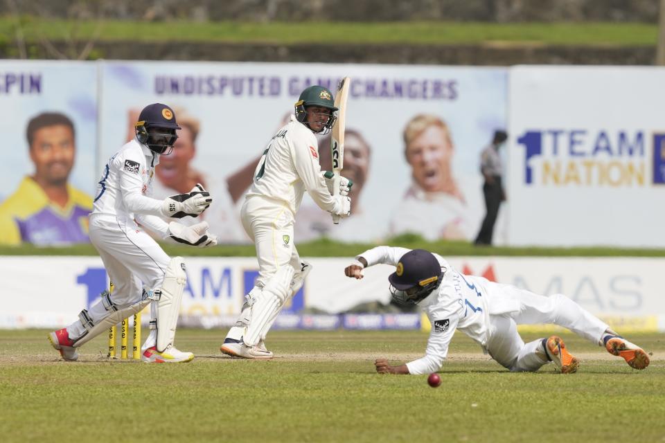 Australia's Usman Khawaja watches his shot as Sri Lanka's Pathum Nissanka attempts to field the ball infant of Niroshan Dickwella during the day two of the first test cricket match between Australia and Sri Lanka in Galle, Sri Lanka, Thursday, June 30, 2022. (AP Photo/Eranga Jayawardena)