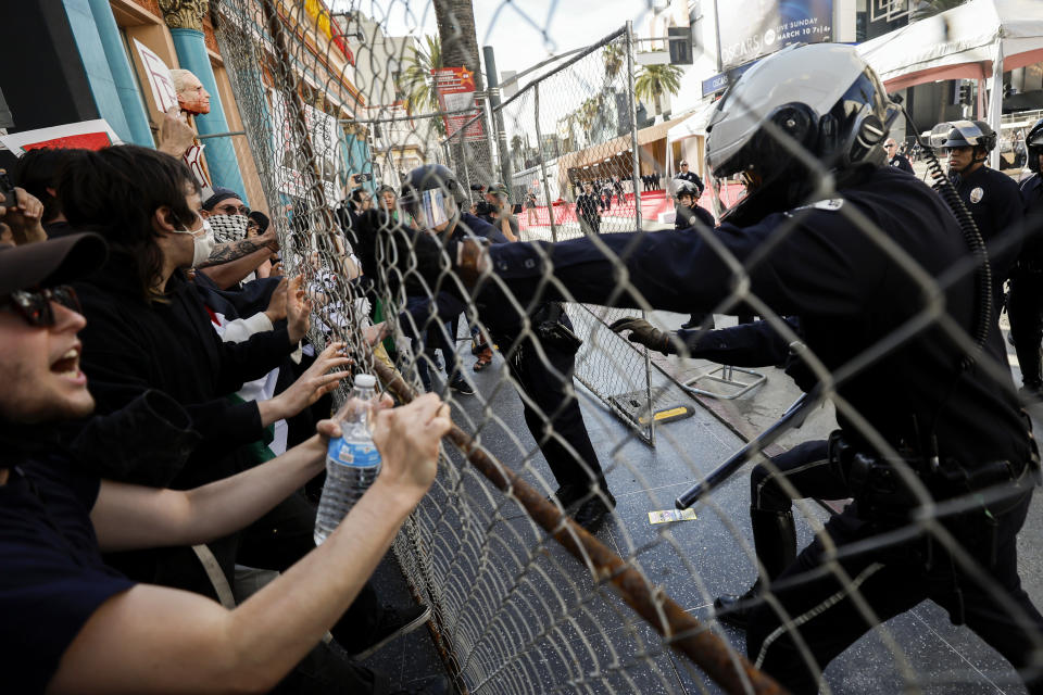 Law enforcement officers and protesters demonstrating in support of Palestinians calling for a ceasefire in Gaza face off after the latter tried to break through a fence securing the perimeter next to the Dolby Theatre as the 96th Academy Awards Oscars ceremony is held nearby on Sunday, March 10, 2024, in the Hollywood section of Los Angeles. (AP Photo/Etienne Laurent)
