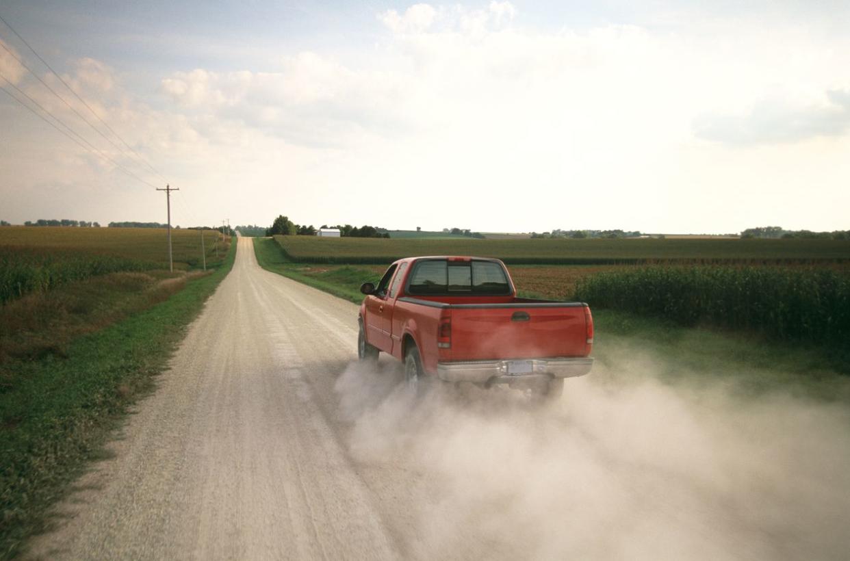 Red Pick Up Truck Traveling Down a Dusty Midwest Road