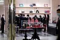 Staff members wearing face masks get ready for a ceremony before a Gucci store inside a shopping mall opens in Wuhan