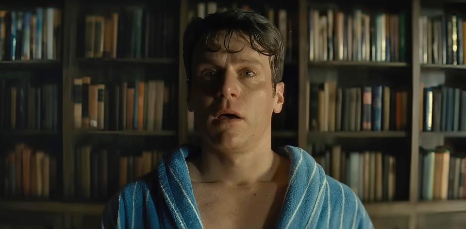 Close-up of man looking distraught in front of bookshelves