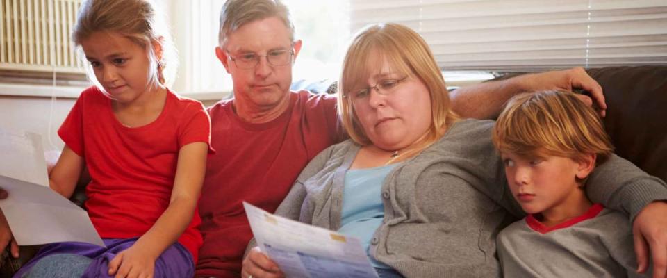 Unhappy Family Sitting On Sofa Looking At Bills