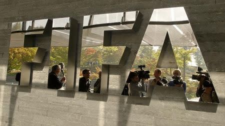 Journalists are reflected in a logo at the FIFA headquarters after a meeting of the executive committee in Zurich October 4, 2013. REUTERS/Arnd Wiegmann