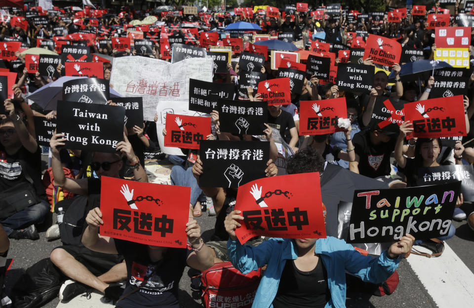 Hong Kong students and Taiwanese supporters hold slogans reading "No Extradition to China" and "Taiwan Supports Hong Kong" to oppose Hong Kong's extradition law outside the Legislative Yuan in Taipei, Taiwan, Sunday, June 16, 2019. Hong Kong residents Sunday continued their massive protest over an unpopular extradition bill that has highlighted the territory's apprehension about relations with mainland China, a week after the crisis brought as many as 1 million into the streets. (AP Photo/Chiang Ying-ying)