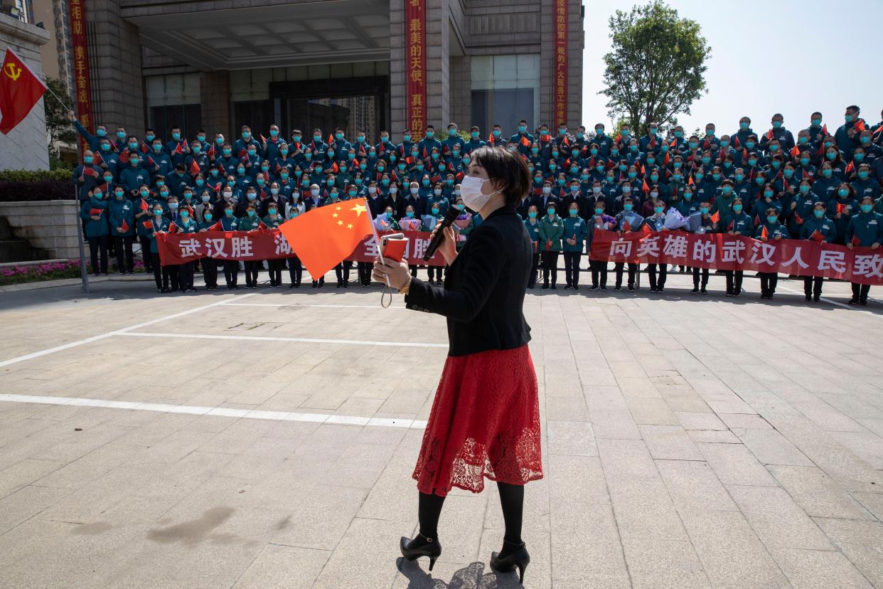 A woman holding a Chinese flag attends the farewell ceremony for the last group of medical workers who came from outside Wuhan to help the city during the coronavirus outbreak on April 15, 2020.