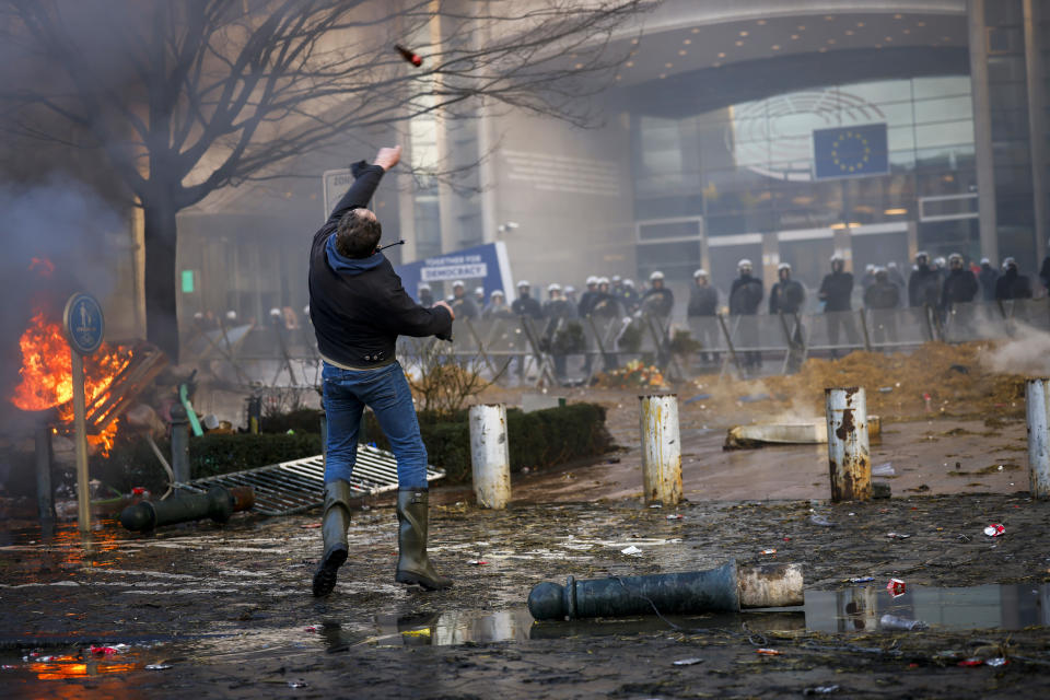 A man throws a bottle towards anti riot police during a protest by farmers outside the European Parliament as European leaders meet for an EU summit in Brussels, Thursday, Feb. 1, 2024. European Union leaders meet in Brussels for a one day summit to discuss the revision of the Multiannual Financial Framework 2021-2027, including support for Ukraine. (AP Photo/Thomas Padilla)