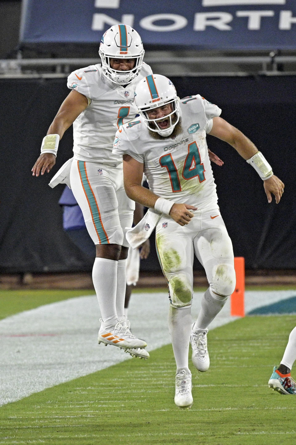 Miami Dolphins quarterback Ryan Fitzpatrick (14) celebrates after throwing a touchdown pass against the Jacksonville Jaguars with teammate quarterback Tua Tagovailoa, left, during the first half of an NFL football game, Thursday, Sept. 24, 2020, in Jacksonville, Fla. (AP Photo/Phelan M. Ebenhack)