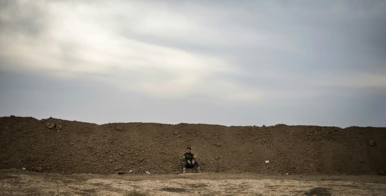 A Peshmerga soldier sits beneath the berm