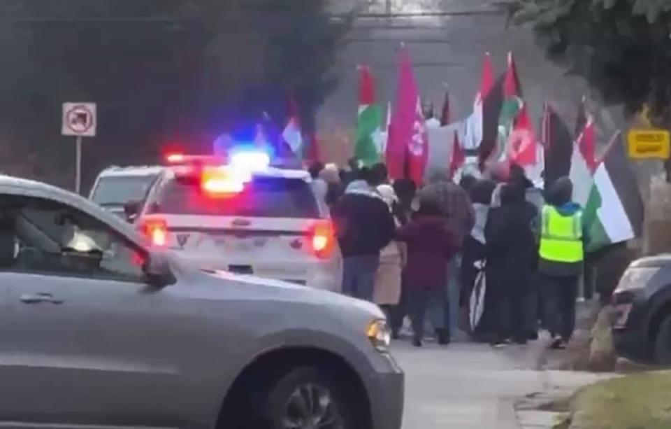 A screen capture from a cellphone video showing Windsor police vehicles escorting pro-Palestinian marchers on Victoria Boulevard in South Windsor on Dec. 31, 2023. (CBC News - image credit)