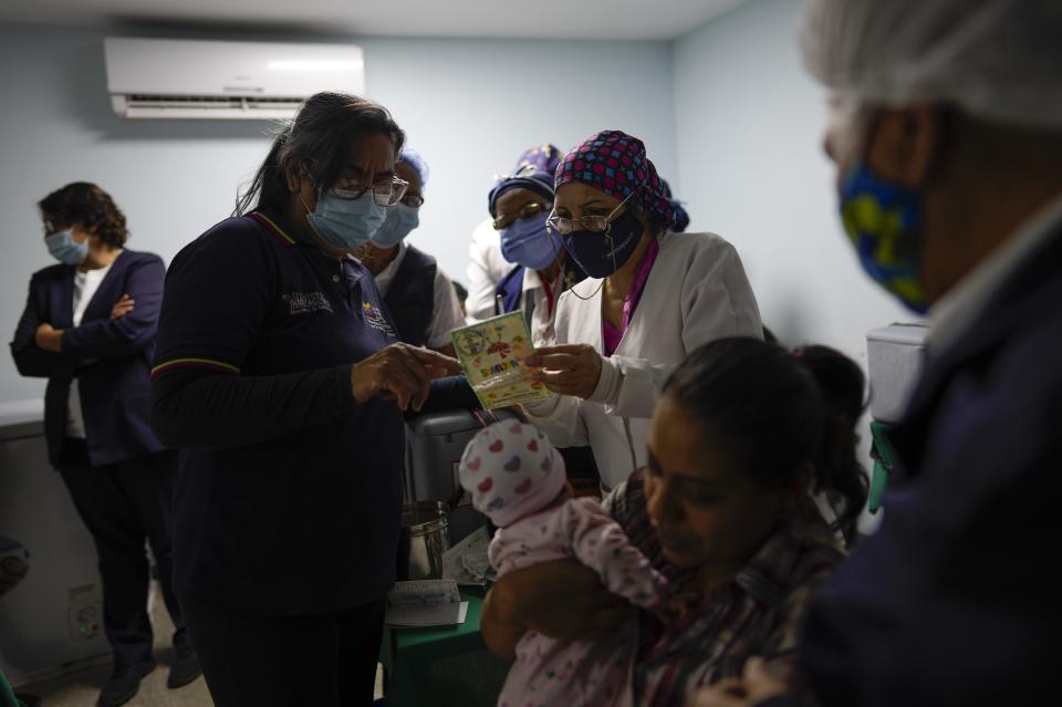 Dos enfermeras estudian una tarjeta de vacunación durante una campaña del gobierno de inmunizaciones gratis contra el polio, la rubeola y la influenza en Caracas el 18 de junio del 2022. (AP Photo/Ariana Cubillos)