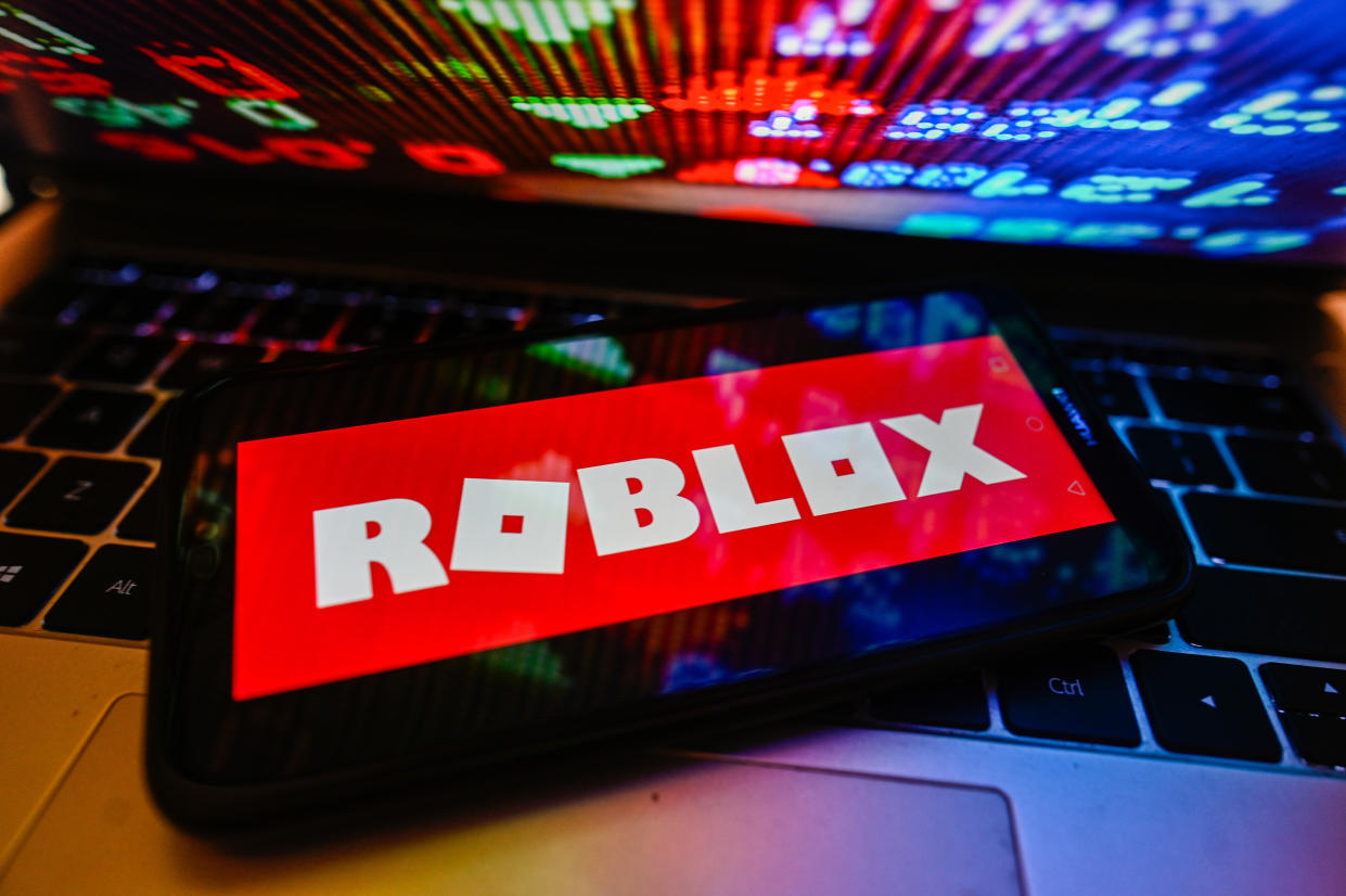 POLAND - 2023/11/09: In this photo illustration a Roblox logo is displayed on a smartphone with stock market percentages on a laptop. (Photo Illustration by Omar Marques/SOPA Images/LightRocket via Getty Images)