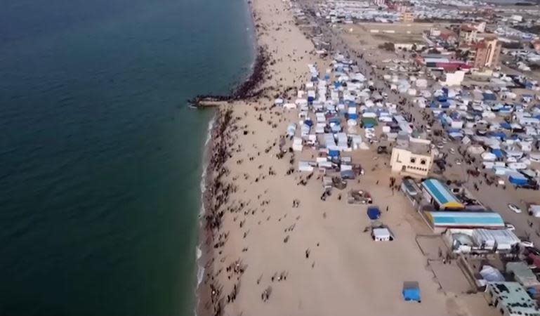 Drone video obtained by Reuters show people gathering by the shore at Deir al-Balah, Gaza Strip, as Jordanian aircraft drop humanitarian aid for thousands of displaced Palestinian civilians, Feb. 26, 2024. / Credit: Reuters