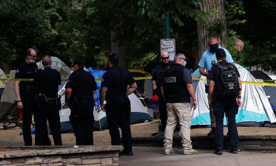 Like many cities across the country, Denver is suffering a wave of gun violence, and 38 people have died in homicides through the end of June, putting the city on track to have one of its deadliest years in at least a decade. Pictured: Denver Police Department officers investigate a shooting amid tents put up by people without homes in a park across from the State Capitol Thursday, July 23, 2020, in downtown Denver.