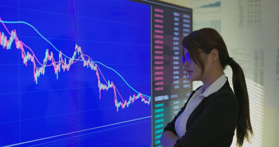 Woman looking at falling stock price chart on screen. 