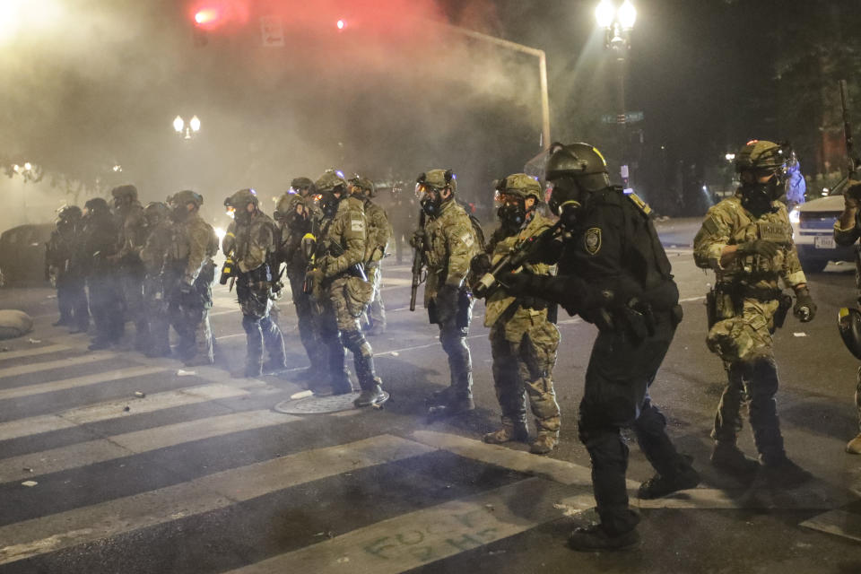 Federal officers line up to deploy tear gas at demonstrators during a Black Lives Matter protest at the Mark O. Hatfield United States Courthouse Sunday, July 26, 2020, in Portland, Ore. (AP Photo/Marcio Jose Sanchez)