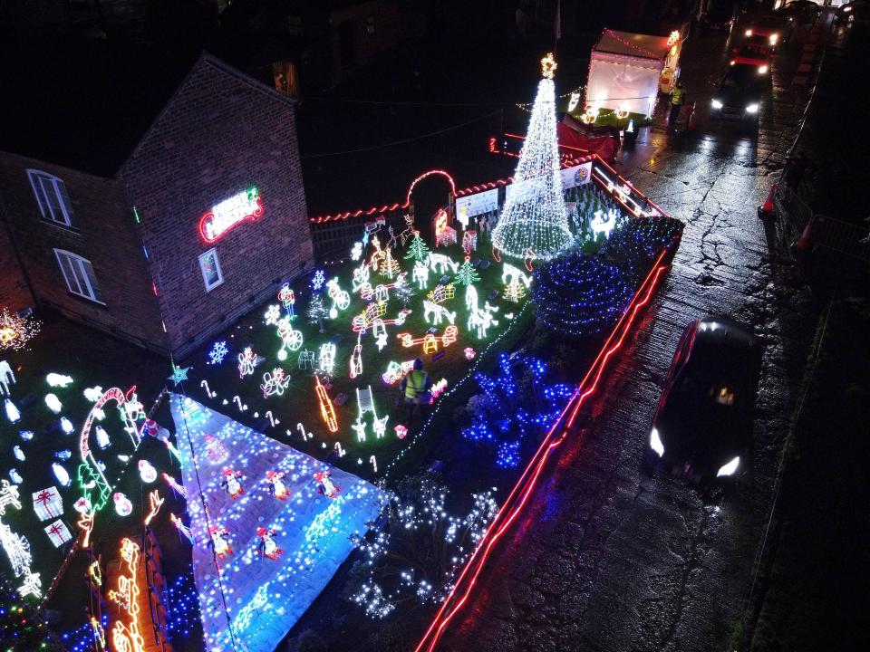 Members of the public drive through the yard at Carters Green farm which is hosting a Christmas light display in Weston, near Crewe, England on December 3, 2020. - Fundraiser Graham Witter organises the annual display at his home in memory of his sister Jessica who passed away in 2015 but has adapted the event due to Covid restrictions. Visitors usually are able to walk around the farmyard and admire the lights. This year they are driving through a starlit garden and enjoying the display form inside their cars. Graham has raised more than £100,000 for a children's hospice running the event for the past seven years. (Photo by Paul ELLIS / AFP) (Photo by PAUL ELLIS/AFP via Getty Images)