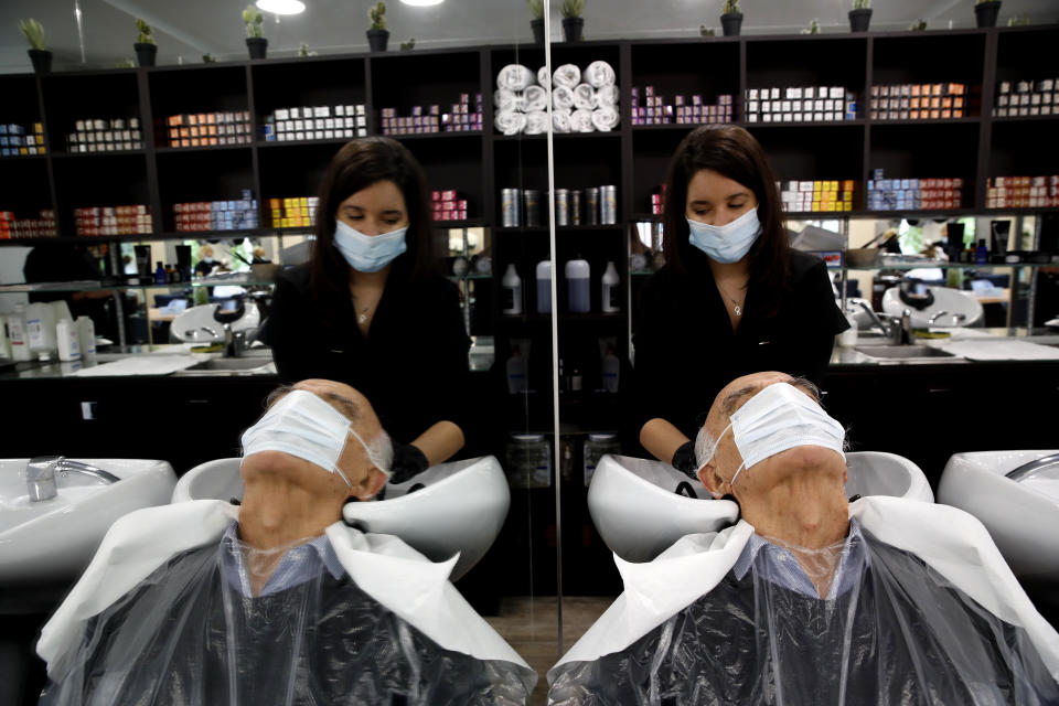 A man gets a hair cut at a hairdressing salon in Sevres, outside Paris, Monday, May 11, 2020. The French began leaving their homes and apartments for the first time in two months without permission slips as the country cautiously lifted its lockdown. Clothing stores, coiffures and other businesses large and small were reopening on Monday with strict precautions to keep the coronavirus at bay. (AP Photo/Christophe Ena)
