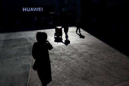 FILE PHOTO: People walk past a Huawei shop in Beijing, China, December 11, 2018.  REUTERS/Thomas Peter/File Photo