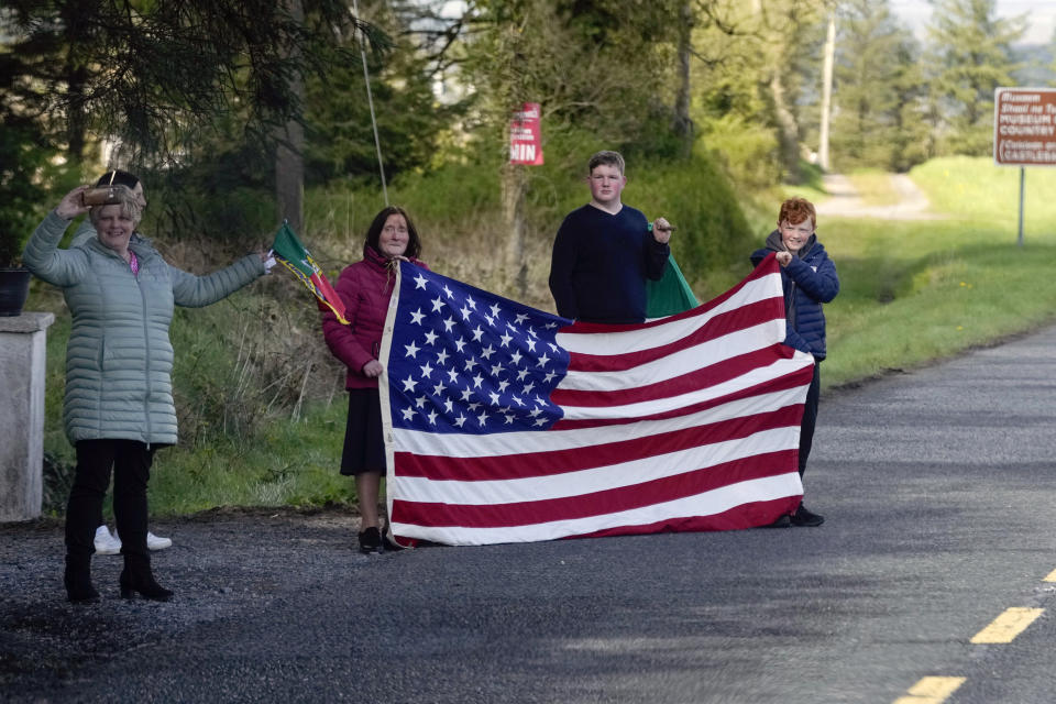 People hold an American flag as they watch President Joe Biden's motorcade drive past in County Mayo, Ireland, Friday, April 14, 2023. (AP Photo/Patrick Semansky)