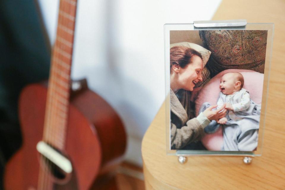 A guitar next to a photo of a woman and a baby.