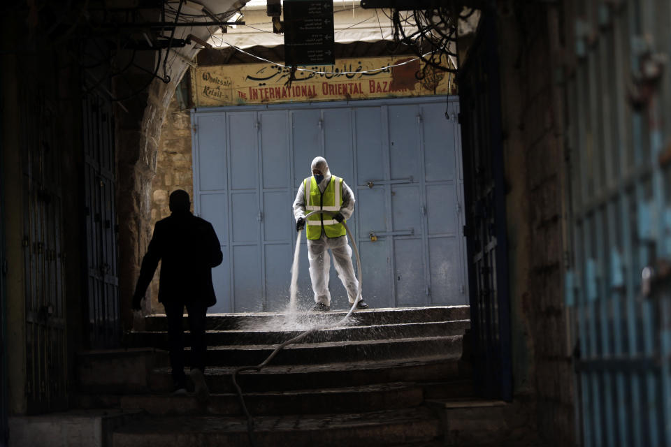 A worker disinfects an alley in Jerusalem's Old City, as general public movements are limited to prevent the spread of coronavirus, Monday, March 30, 2020. (AP Photo/Mahmoud Illean)