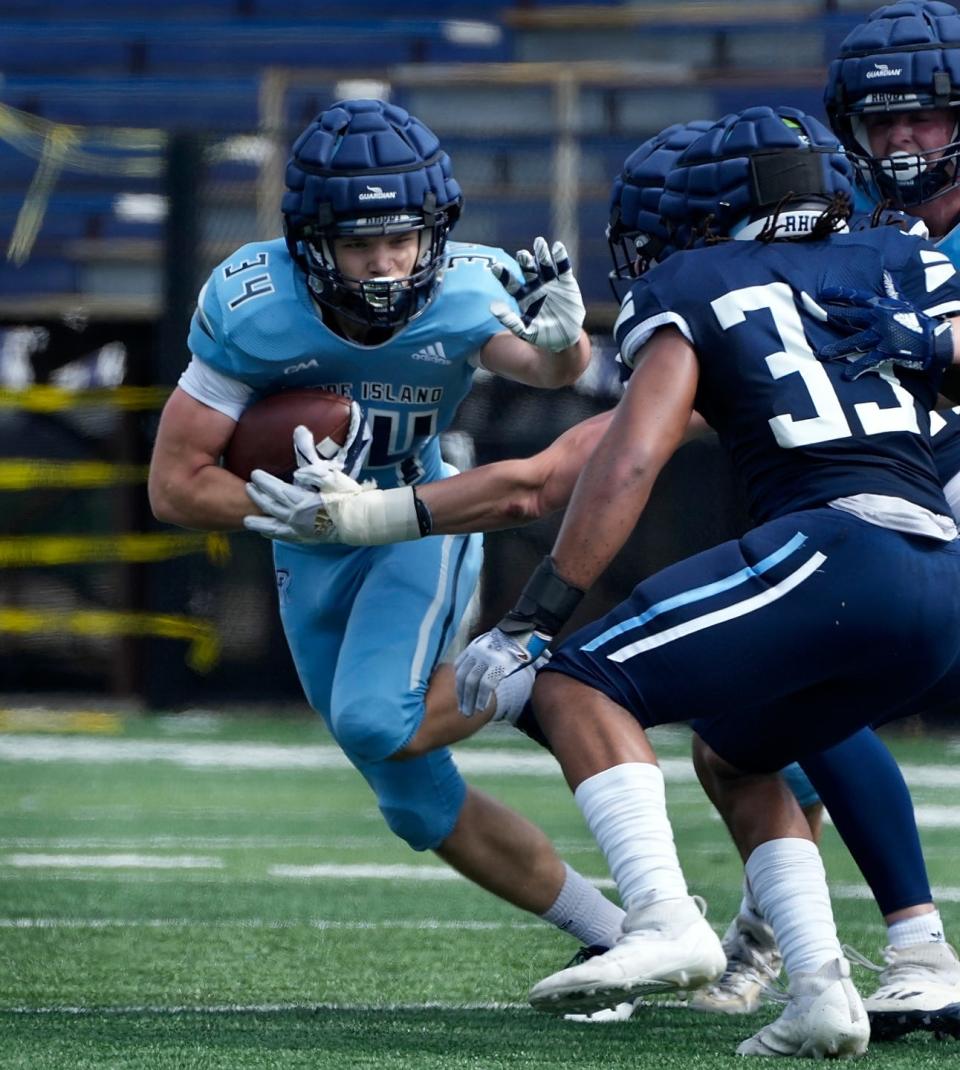 Runinng back,Gabe Sloat looks to fend off tacklers during a first-half run in URI's Blue-White scrimmage on Saturday.