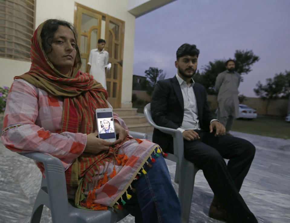 Kaneez Sughra, wife of kidnaped prominent Pakistani journalist Matiullah Jan, shows a picture her husband to journalists while other family member gather at a family's home, in Islamabad, Pakistan, Tuesday, July 21, 2020. Jan, known for his hard hitting criticism of the country's powerful institutions, including its military, is missing, human rights groups and a family member said Tuesday. (AP Photo/Anjum Naveed)