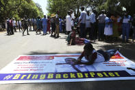 A Zimbabwean doctor lays on a banner with a portrait of fellow missing doctor, Peter Magombeyi, in Harare, Wednesday, Sept, 18, 2019. Zimbabwean doctors protesting the alleged abduction of a union leader were met by a line of baton- wielding police in the capital as fears grow about government repression. (AP Photo/Tsvangirayi Mukwazhi)