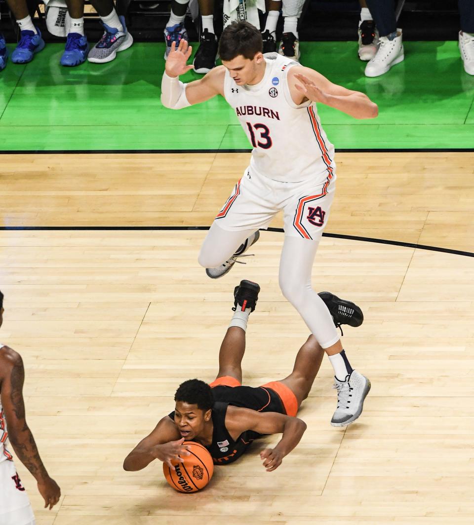 Auburn University center Walker Kessler (13) steps over University of Miami guard Charlie Moore (3) during the first half of the NCAA Div. 1 Men's Basketball Tournament preliminary round game at Bon Secours Wellness Arena in Greenville, S.C. Sunday, March 20, 2022.